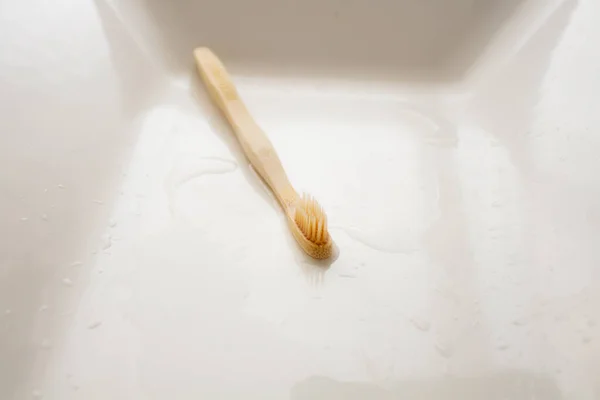Beyaz banyo lavabosunda tahta diş fırçası.