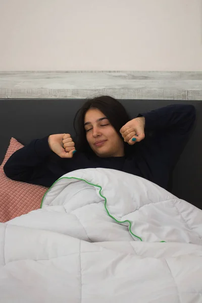 Pijamalı bir kız uyanıyor ve esniyor.