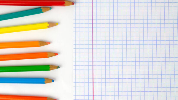 Pencils dropped on a white table with a sheet of square paper, photo of school supplies for back to school