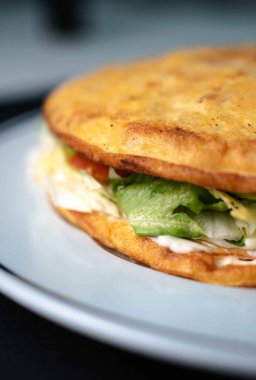 Geleneksel İspanyol patates omleti, zıt bir siyah arka plana karşı beyaz tabakta servis edilir. Bu lezzetli sebzeli omlet İspanyol mutfağında popüler bir yemektir. Taze malzemelerle yapılır ve lezzet doludur.