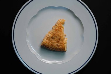 Karşınızda etkileyici bir İspanyol patates omleti. Zarif bir beyaz tepside dramatik bir siyah arka plana yerleştirilmiş. Omletin zengin altın rengi ile koyu arkaplan arasındaki zıtlık çarpıcı bir görsel ziyafet yaratıyor. Her biri 