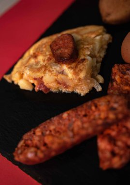 İspanyol mutfak mirasına bu ağız sulandıran patates omletini parlak, siyah bir tepside servis et. Her dilim taze patateslerin, taze çiftlik yumurtalarının ve baharatlı sucuğun enfes bir karışımını ortaya çıkarıyor.