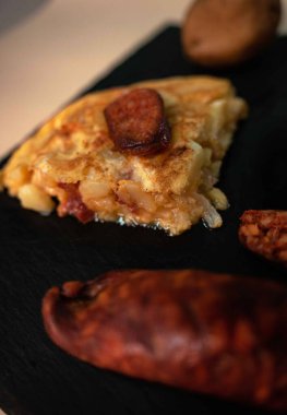 İspanyol mutfak mirasına bu ağız sulandıran patates omletini parlak, siyah bir tepside servis et. Her dilim taze patateslerin, taze çiftlik yumurtalarının ve baharatlı sucuğun enfes bir karışımını ortaya çıkarıyor.