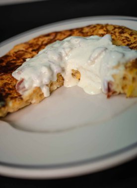 Lezzetli patates omletimizle İspanyol geleneğinin ve İtalyan yeteneğinin enfes bir karışımını deneyin. İçinde taze patates, yumurta ve lezzetli bir carbonara sosu var. El değmemiş beyaz bir tabakta, çarpıcı bir siyah zemine karşı servis edilmiş, mükemmel. 