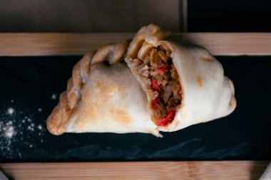 Arjantin bifteğimiz Empanada 'nın leziz et ve biberlerle dolu, ağız sulandırıcı dokusunu ortaya çıkarmak için ustalıkla hazırlanmış ve kesilmiş lezzeti. Her ısırıkta Arjantin gastronomisinin özünü tecrübe et.