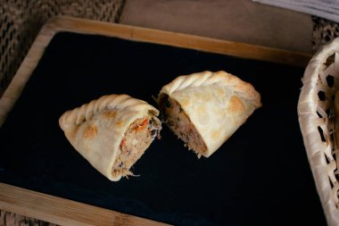 Kendini otantik Arjantin aromasına bizim Empanada Chaparrita ile daldır. Zarif bir karatahta ve tahta tahtada dilimlenmiş ve servis edilmiş bu doldurulmuş börek her ısırıkta sizi yenecektir. İnce hamurlu ve cömert dolgulu. 