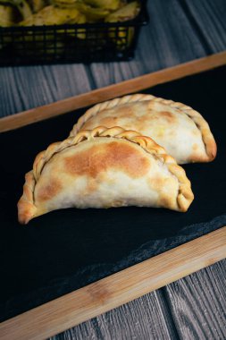 Arjantin 'in zengin lezzetlerine, ağız sulandıran böreklerimiz parlak, siyah bir tabakta servis ediliyor. Her gözleme geleneksel Arjantin malzemeleriyle dolu ve lezzetli güzelliklerle dolu bir mutfak lezzeti. Bu gastronomik ph