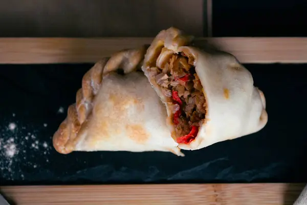 Arjantin bifteğimiz Empanada 'nın leziz et ve biberlerle dolu, ağız sulandırıcı dokusunu ortaya çıkarmak için ustalıkla hazırlanmış ve kesilmiş lezzeti. Her ısırıkta Arjantin gastronomisinin özünü tecrübe et.