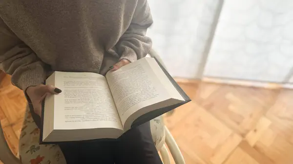 Kitap Günü 'nün özünü yakalayın. Bir kız en sevdiği kitabın sayfalarında teselli bulur. Sandalyede nazikçe sallanırken. Okumaya dalmış, edebiyatın coşkusunu ve mucizesini somutlaştırıyor, izleyicileri hikaye anlatmanın büyüsünü benimsemeye çağırıyor..