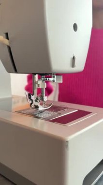 Bir dikiş makinesinin yanına yerleştirilmiş düz kapalı dikiş makinesi iğnesi, evde dikiş dikmeyi öğrenen genç bir kadının bir anını yakalıyor. DIY projeleri, ev dikimi ve yaratıcı hobiler için mükemmel.