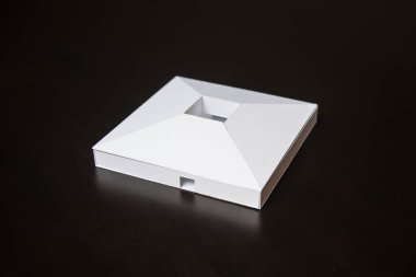 Siyah arka planda çatısı olan beyaz ölçekli bir bina..