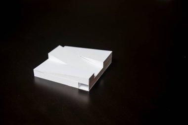 Siyah arka planda çatısı olan beyaz ölçekli bir bina..