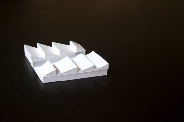 Siyah arka planda çatısı olan beyaz ölçekli bir bina..