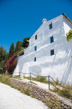 Frigiliana, Malaga 'daki eski evin mavi pencereli beyaz cephesi