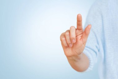 Kadın eli mavi arkaplanda işaret parmağıyla sanal düğmeye basıyor.