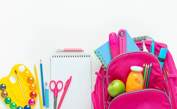 Pink backpack with school supplies on white background. Directly above, copy space