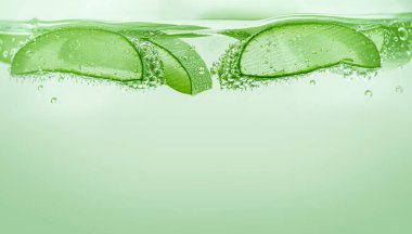 Aloe Vera yeşil arka planda suyun altında dilimler. Kapat..