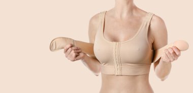 Young woman wearing a compressing bra with a stripe after breast augmentation surgery.  clipart