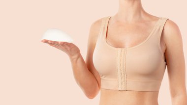 Woman wearing a compressing bra after breast augmentation surgery and holding implant in hand. Copy space clipart