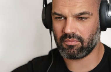 Kulaklıklı orta yaşlı sakallı adam işine odaklanmış. Portreyi kapat. Boşluğu kopyala