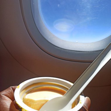 Eating sweet curd and having airplane window view clipart