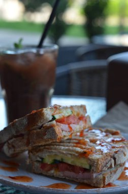 a sandwich with a glass of juice, sandwich, and a sandwich with cheese, tomato and cucumber