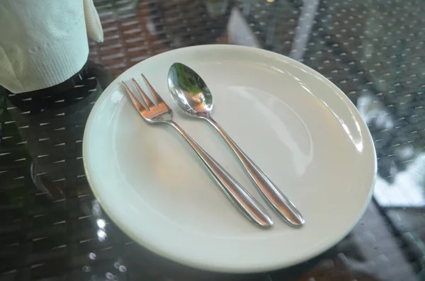 Çatallı beyaz tabak, masada bıçak.