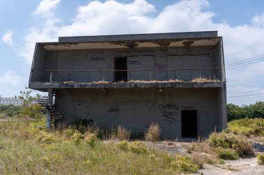 Bitkilerle çevrili, etiketli terk edilmiş bir bina.