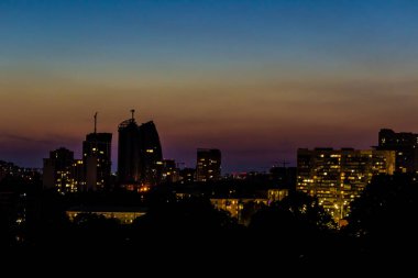 Karanlık gökyüzüne karşı pencerelerinde ışık olan yüksek binalar.