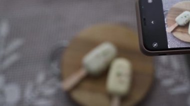 Sosyal medyada fotoğraf paylaşmak için elinde akıllı telefonuyla tatlı cheesecake 'in fotoğraflarını çeken bir kadın. Lezzetli kekten zevk alan çekici genç bir kız. 4k görüntü