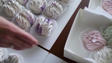 Bir kadın hediye kutusunda açık yeşil ve pembe şekerlemeler taşıyor. Paketleme için yakın aksesuarlar. Ev işi konsepti. Yüksek kalite 4k görüntü