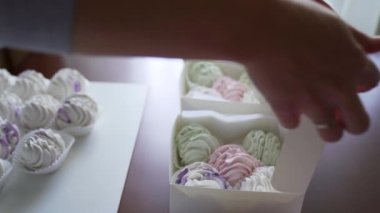 Bir kadın hediye kutusunda açık yeşil ve pembe şekerlemeler taşıyor. Paketleme için yakın aksesuarlar. Ev işi konsepti. Yüksek kalite 4k görüntü