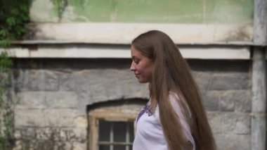 Güneşli bir günde, sonbaharda parkta yürüyen ve gülümseyen beyaz elbiseli çekici esmer bir kadının portresi. Sonbaharda açık havada mutlu ve güzel bir kadının yüzü. Yavaş çekim. Tam HD görüntüler