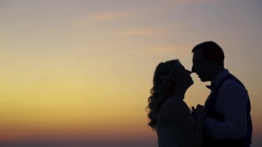 Günbatımında dağın zirvesinde birbirine aşık Asyalı çiftlerin silueti. Zirvedeki aşk çifti gün batımına ve adalara bakıyor. Yüksek kaliteli FullHD görüntüler