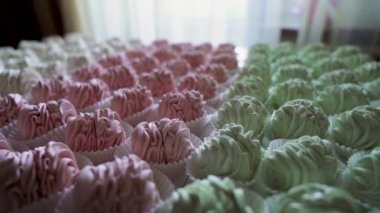 Birçok kırmızı, yeşil ve beyaz pişmiş şekerlemeler masanın üzerinde yatıyor. Ağır çekim. Kamera dönmeye devam ediyor. Yüksek kalite 4k görüntü