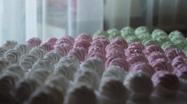 Masaya şeker tozu serpiştirilmiş yeşil, pembe ve beyaz ev yapımı şekerlemelere odaklan. Yüksek kalite 4k görüntü