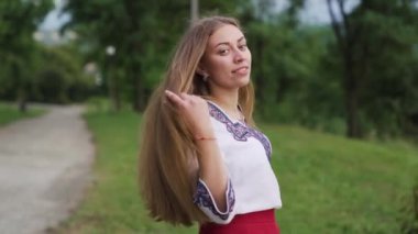 Genç kadın şehir parkında yürüyor, dönüyor ve gülümsüyor. Kamera arkadan takip etsin. Yavaş çekim. Yüksek kaliteli FullHD görüntüler
