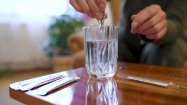 Senior woman with glass of medicine water in hands sits on bed at home. Aged female take medicine and drink water resting in bedroom. Retirement and healthcare concept. Slow motion 4k footage