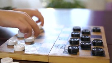 Boys hand moves a white piece of checkers. Child playing checkers with granny close up. development strategy thinking. High quality 4k footage