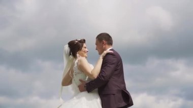 Gentle posing bride and groom on the background of clouds. Slow motion. High quality FullHD footage