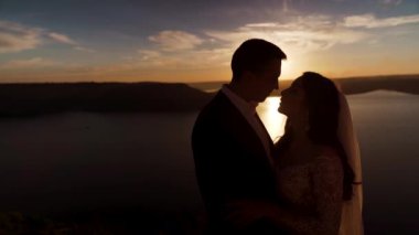 Silhouette of couple in love at sunset, sexy kiss. Island on background. Slow-motion. High quality FullHD footage