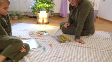 Preschool boy laughing and playing board game with grandmother at the floor. Granny and grandchild having fun. High quality 4k footage