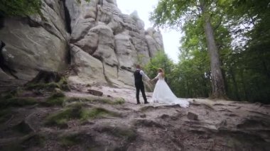 Newlyweds standing on a cliff in sun glare in the background. High-quality FullHD footage