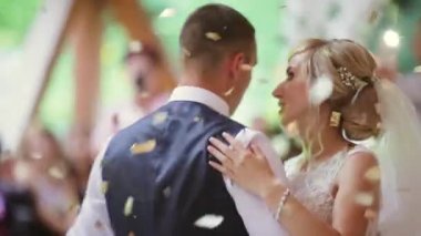 First dance of wedding pair in flying gold confetti. . High quality FullHD footage