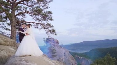 Rock Dağı 'nın görkemli manzarası ve birbirine yaklaşan güzel yeni evliler. Birbirine aşık çift dağın tepesinde sarılıyor ve ayakta duruyor. Yüksek kaliteli FullHD görüntüler