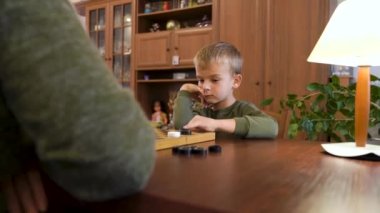 Little boy child play checkers with grandmother. The boy won and very happy. High quality 4k footage