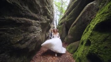 SLOW MOTION: Young woman running inside a narrow canyon in the mountain, waving her hand inviting her companion to follow her. Tracking shot, a pov couple enjoying a hike inside the gorge High quality