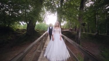 Gelin ve damat ormandaki tahta köprüde. Yüksek kaliteli FullHD görüntüler