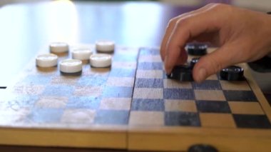 Boys hand moves a white piece of checkers. Child playing checkers with granny close up. development strategy thinking. High quality 4k footage