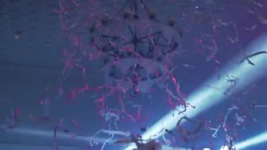 Background Slow-motion confetti on the party with scenic blue lights. Nobody. High quality FullHD footage